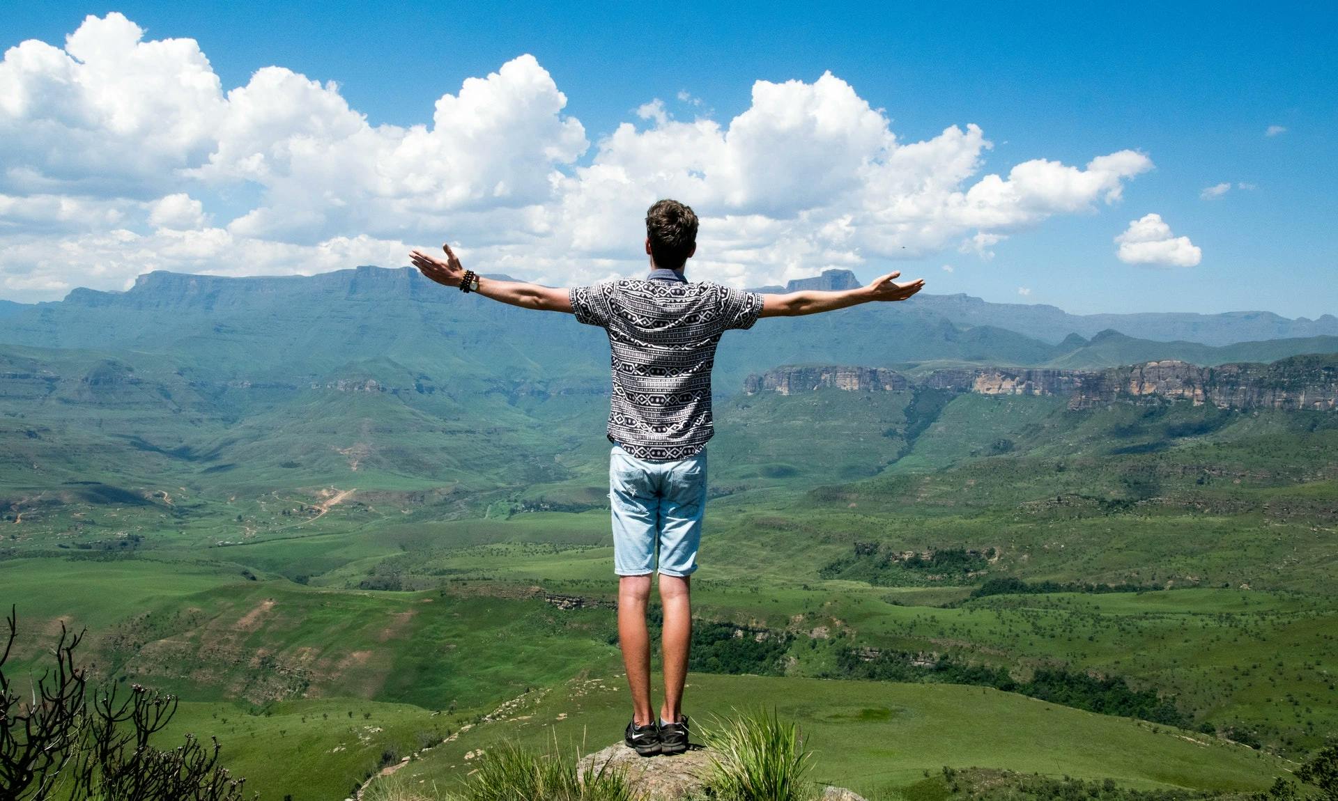 Man standing on ledge looking over countryside